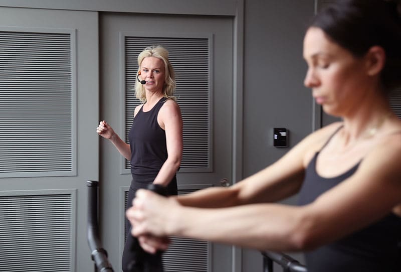 instructor-coaching-megaformer-client-tight-dallas.tight-dallas. Instructor coaching a client during a resistance exercise on a Megaformer