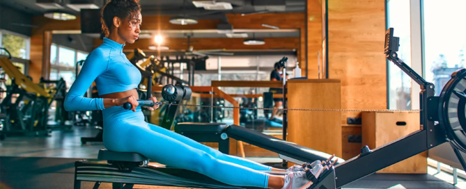 Woman performing seated row exercise on reformer machine in gym