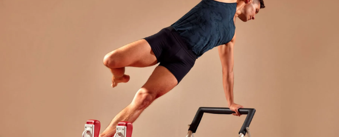 Man performing advanced side balance on a Pilates reformer machine