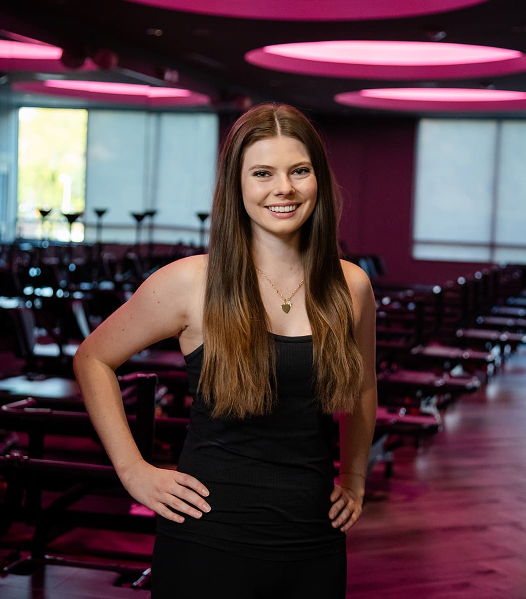 fitness-instructor-hailey-standing-with-hands-on-hips-in-modern-studio.tight-dallas. Fitness instructor Hailey standing with hands on hips in a studio.