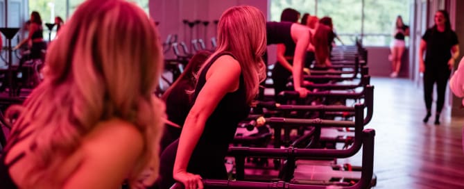 Women performing tricep dips on Megaformer machines in studio