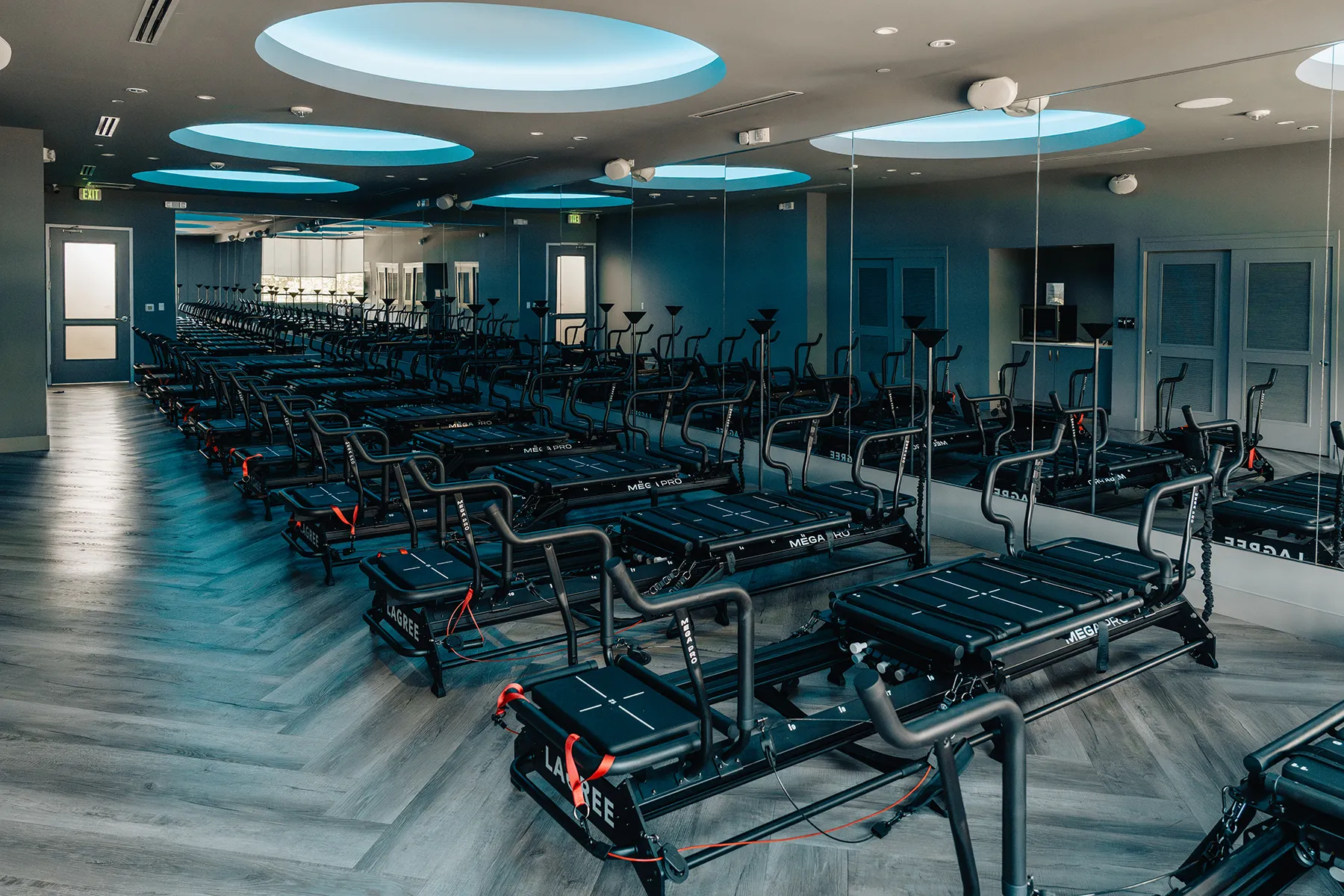 lagree-fitness-studio-dallas-megaformer-room.tight-dallas. Wide view of Megaformer studio with rows of machines at TIGHT Dallas.