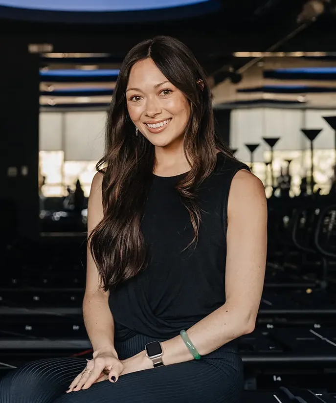 fitness-instructor-caiti-morris-hatton-smiling-seated-in-modern-studio.tight-dallas. Fitness instructor Caiti Morris Hatton smiling while seated in a studio.