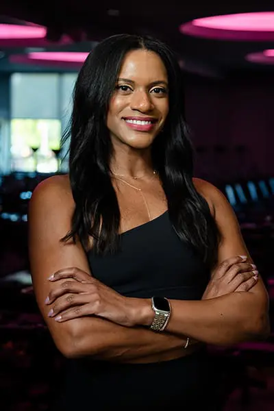 Fitness instructor Kim smiling with arms crossed in a studio.