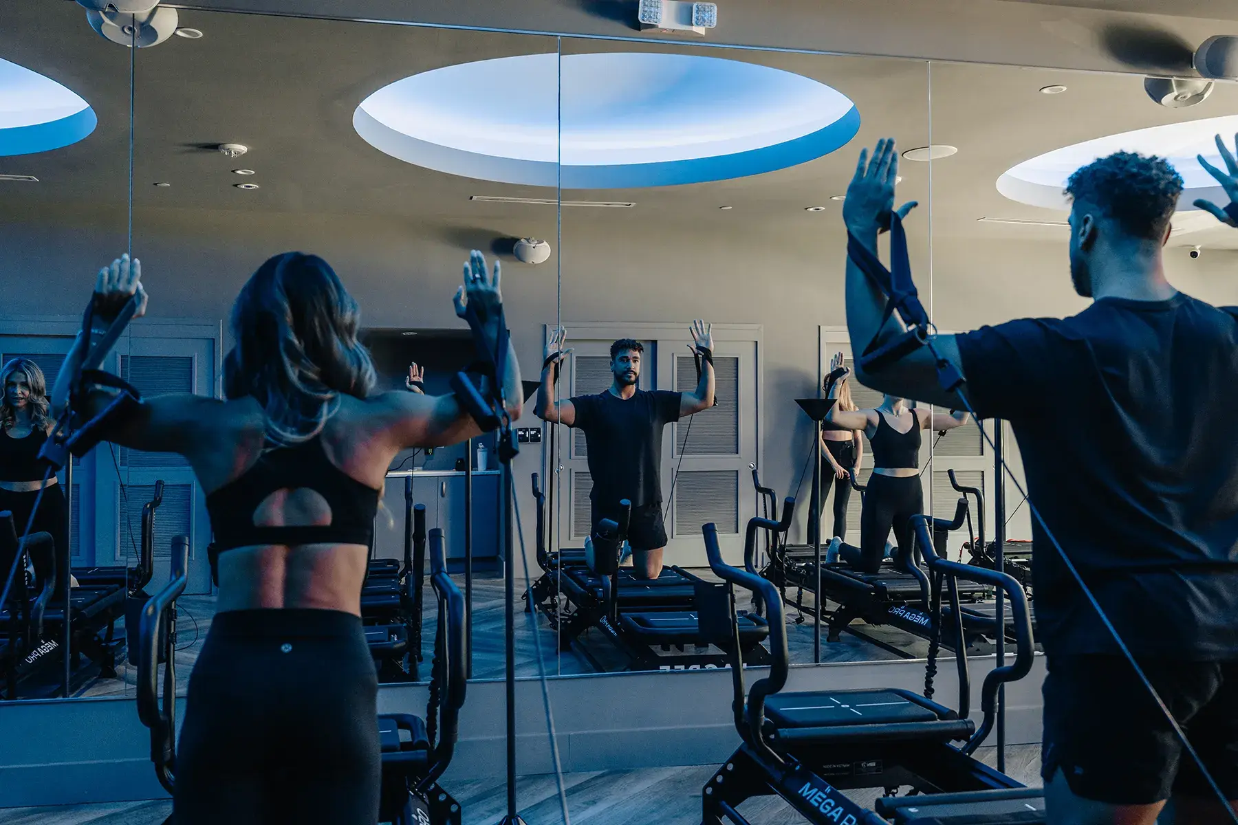 group-lagree-class-performing-cable-resistance-exercises-with-instructor-guidance.tight-dallas. Group fitness class performing resistance exercises with cables on Megaformer machines.