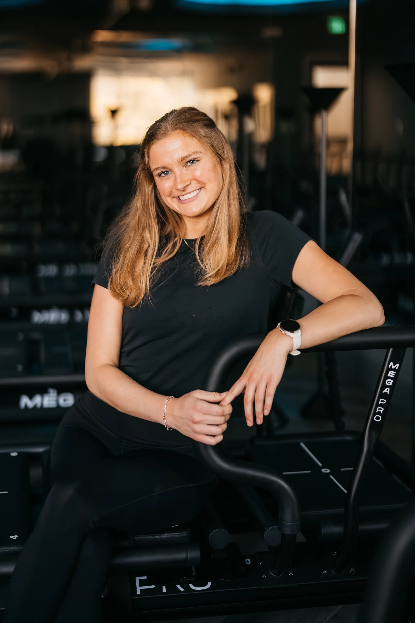 lagree-instructor-annie-seated-on-megapro-machine-tight-dallas. Lagree instructor Annie smiling while seated on a MegaPro machine at Tight Dallas