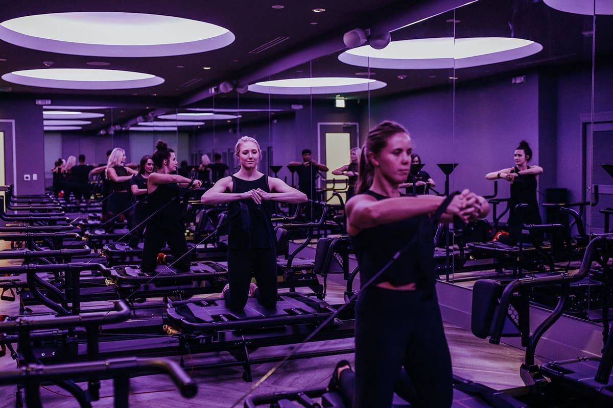 studio_1 Women working out on Megaformers in a Tight Dallas Lagree fitness class, showcasing strength training and core control in a modern studio.
