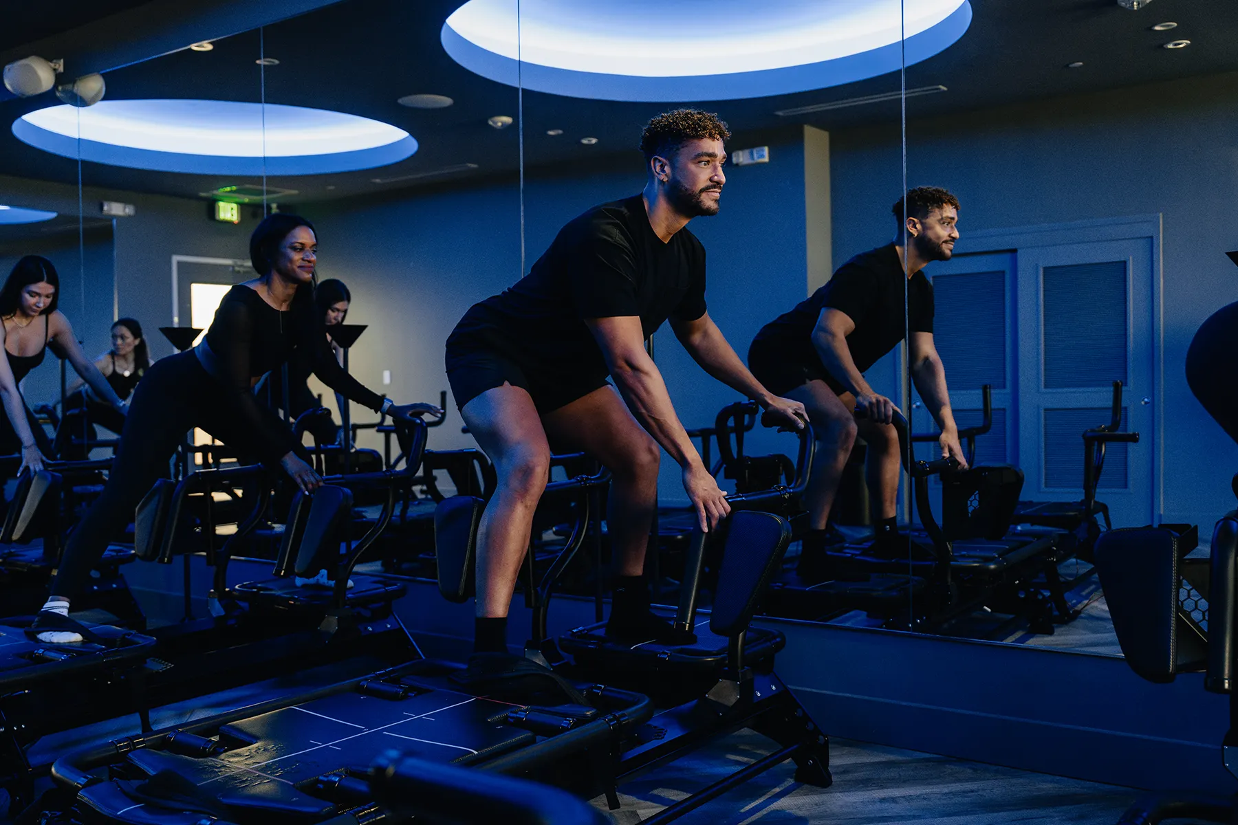 Focused participant performing a controlled movement on a Megaformer during a high-intensity class at Tight Dallas
