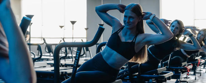 Group of women performing Lagree fitness exercises on Megaformer machines at TIGHT Dallas studio, focusing on core strength and controlled movement.