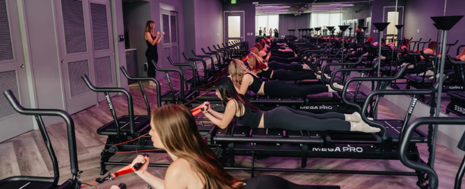 Group Lagree fitness class in Dallas with clients using Megaformer machines for a full-body, low-impact workout inside a modern boutique studio.