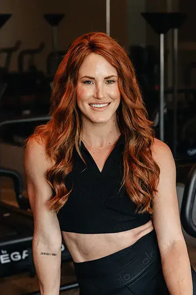 Fitness instructor Sarie smiling in a studio wearing black athletic wear.